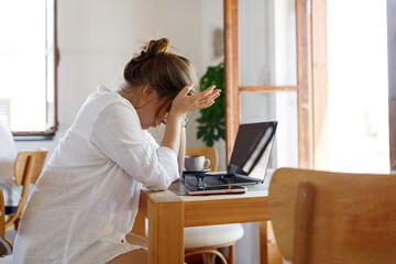 Frustrated business woman feels panic shock after business failure, bad news online sitting in office with laptop, stressed upset woman employee worried about bankruptcy,exhausted tired of overwork. 