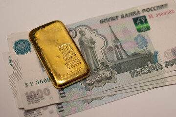 Russian rubles banknotes with gold bullion bar. Gold backed financial system of Russia. Russian gold reserves. De-dollarization. World monetary system.
