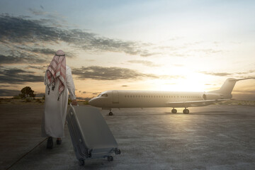 Rear view of an Arab man wearing keffiyeh walking with a suitcase for traveling by plane