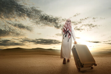 Rear view of an Arab man wearing keffiyeh walking with a suitcase for traveling