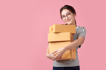 Beautiful Young Asian woman holding parcel box isolated on pink background, Delivery courier and shipping service concept. - obrazy, fototapety, plakaty