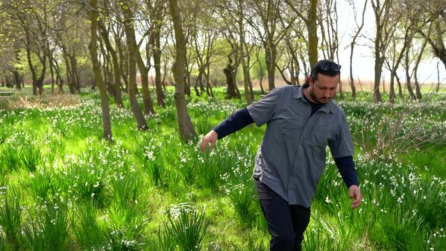 Image of man walking among snowdrops in nature.