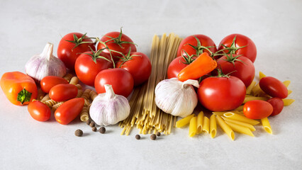 Raw Spaghetti Penne Fusili Tomatoess Cloves of Garlic Orange Pepper on Gray Background Ingredients for Italian Pasta Banner