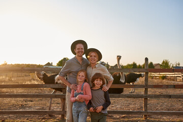 Happy family near paddock with ostriches on ranch - obrazy, fototapety, plakaty