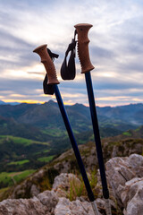 trekking poles without people, placed on a rock on the mountain at sunset. Concept of hiking, trekking and mountain sports activities.