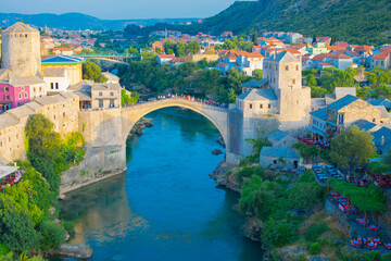 Fantastic Skyline of Mostar with the Mostar Bridge, houses and minarets, during sunny day. Location: Mostar, Old Town, Bosnia and Herzegovina, Europe - obrazy, fototapety, plakaty