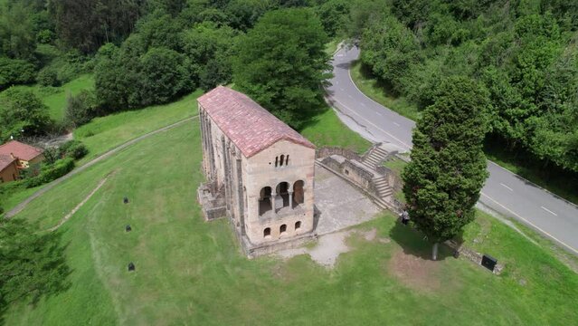 Aerial view of Santa Maria del Naranco aged catholic church with tourists visiting it.