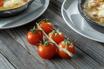 Red cherry tomato on a wooden background, rustic style. Fish dishes stand in the backdrop.