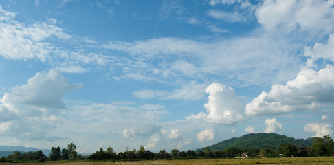The white clouds have a quaint and rural shape. The sky is cloudy and blue