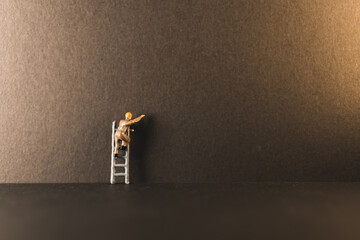 Miniature people, man on a ladder with space for text