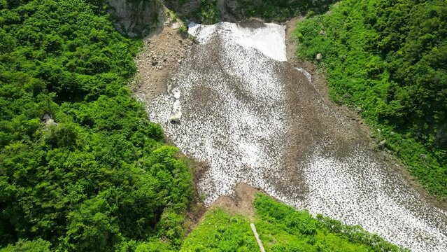新潟県糸魚川市の権現岳の麓にある万年雪は猛暑に負けず多く残っている様子を空撮で
