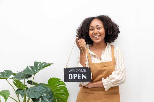 African American barista with apron is holding open sign in front of the coffee shop for cafe and small restaurant service concept