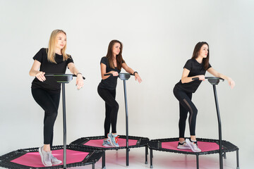 Three adorable fitness women In sportswear jumping on sport trampoline White background