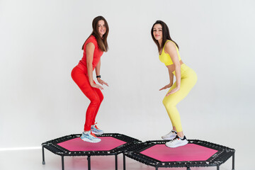 Two adorable fitness women In sportswear jumping on sport trampoline