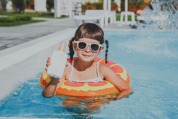 close-up portrait of a toddler girl 4 years old swims in the pool in the summer in an inflatable circle and holding sunscreen in hands