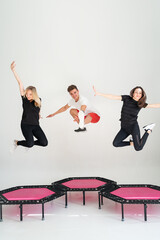 Three adorable fitness people In sportswear jumping on sport trampoline White background