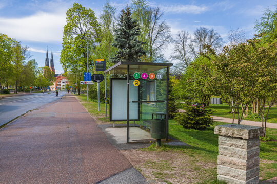 Close up view of buss stop on green trees and cathedral church towers and blue sky on background. Sweden. Uppsala.