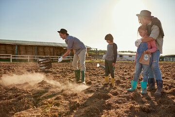 Family looking at father digging ground on field