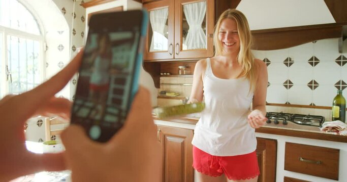 An excited young woman flipping a pancake while having her photo taken on a cellphone