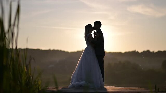 The newlyweds are kissing at sunset. Silhouettes.