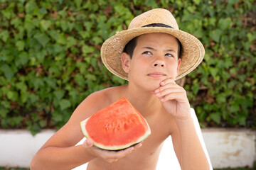happy child waring straw hat eating watermelon in the garden