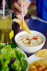 Close up photo of famous Hanoi fried shrimp cake being dipped in fish sauce                             