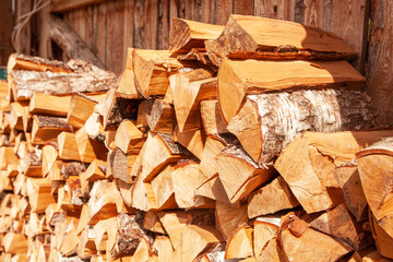 Chopped firewood stacked in a woodpile, for kindling a stove or fireplace, for heating a house. Concept of economic fuel crisis.