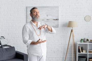 spiritual coach in white clothes showing energy gesture while meditating with closed eyes.