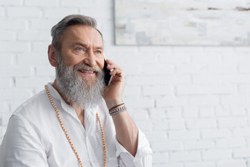 happy master guru in beads talking on smartphone at home.