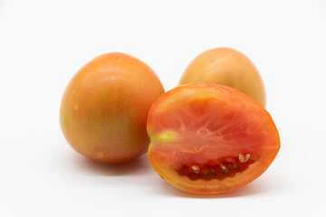 half ripe tomato with slices on white background