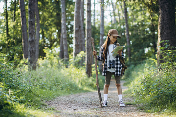 Girl looking at the map while walking in the forest