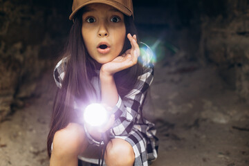 Girl with flashlight in cave searching antiquity - obrazy, fototapety, plakaty