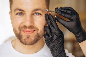 Obraz premium Man at spa making treatment for his eyebrows