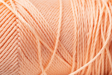 Macro texture of bright coral silk thread, close-up, copy space. Macro Photography of a coil with threads. Sewing background, screensaver. Abstraction, interweaving of shiny threads