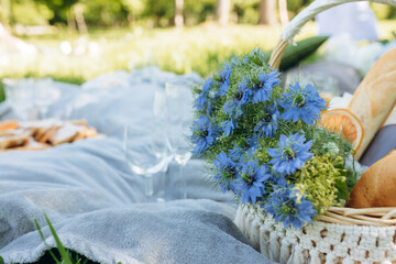 Summer picnic on sunny day with bread, fruit, bouquet hydrangea flowers, glasses wine