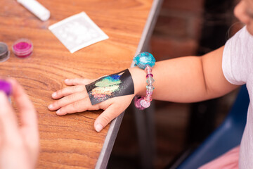 Little girl getting glitter tattoo at birthday party