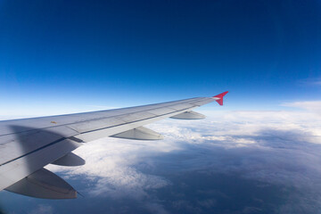 Airplane wing on blue sky cloud window view travel background
