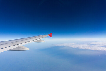 Fototapeta na wymiar Airplane wing on blue sky cloud window view travel background