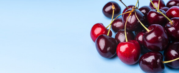 Juice and fresh cherry with leaf and water drops on blue background. Sweet red berry cherries. Summer fruit Background