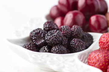 Raspberries on a fruit plate on a white background. Ripe berries. Vitamins and a healthy lifestyle