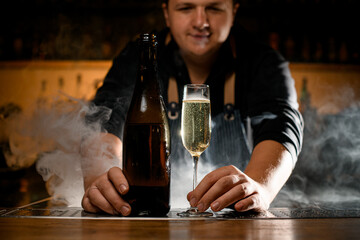 beautiful view of champagne glass with drink and bottle at smoked bar