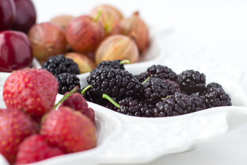 Mulberry on a fruit plate on a white background. Ripe berries. Vitamins and a healthy lifestyle