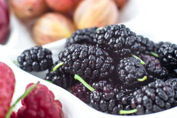 Close-up of mulberry on a fruit plate on a white background. Ripe berries. Vitamins and a healthy lifestyle