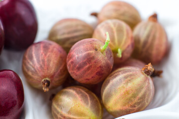 Close-up of gooseberries on a fruit plate on a white background. Ripe berries. Vitamins and a healthy lifestyle