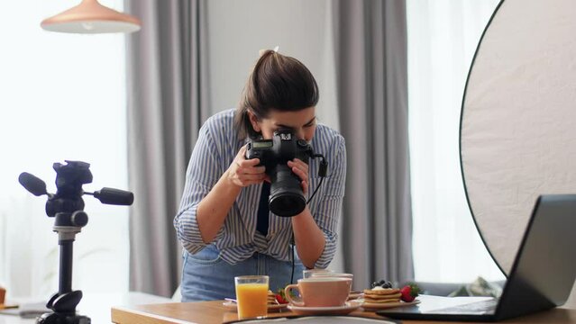 blogging, photographing and people concept - happy smiling female food blogger or photographer with laptop and camera in kitchen at home