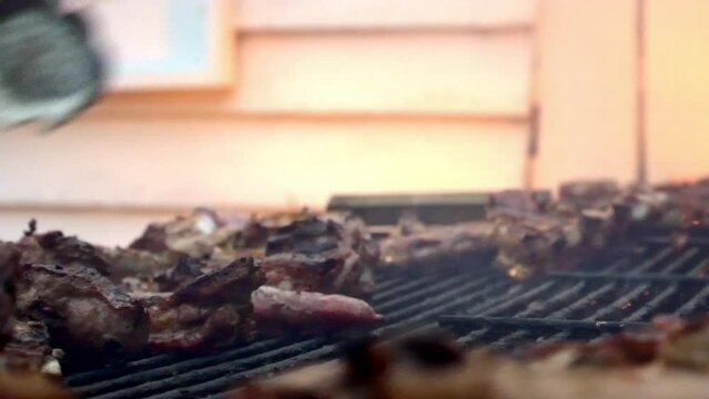 dale of some flames in a barbecue in the foreground where we see meat that is being prepared to be served during an afternoon with some magnificent colors of the meat and the afternoon