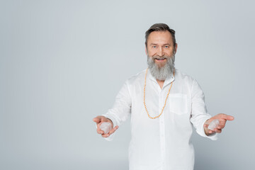 pleased spiritual coach holding selenite crystals isolated on grey.