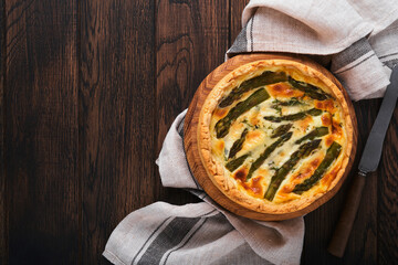 Quiche. Homemade asparagus pie or quiche with cheese and spinach on old dark wooden table background. Top view.