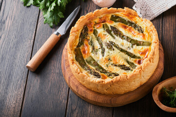 Quiche. Homemade asparagus pie or quiche with cheese and spinach on old dark wooden table background. Top view.