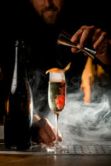 great view on bottle and wineglass of smoked carbonated cocktail on the bar counter. Bartender pours liquid
